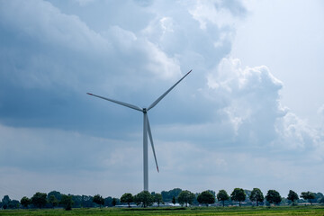 view of a rural area with a wind turbine against a sky with storm clouds
