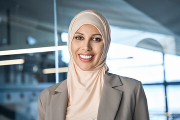 Closeup headshot face portrait of young muslim specialist business lady in headscarf hijab in office smiling friendly. Middle eastern indian executive ceo entrepreneur woman leader looking at camera