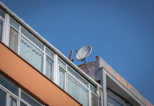 A old satellite dish on the roof of a apartment.