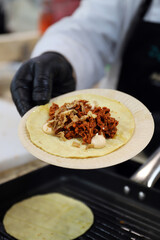 chef presentando  un burrito de tiras de carne y salsa de tomate con mayonesa