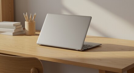 Laptop on wooden desk near books and pencils