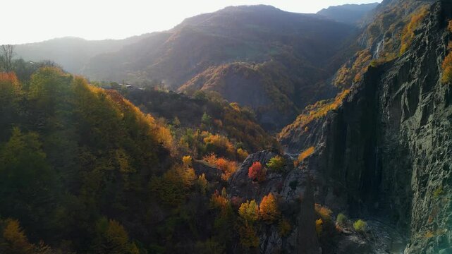 Aerial drone footage of Lahic Yolu Canyon in Azerbaijan, bathed in golden autumn sunlight, with the crystal-clear river glistening below.