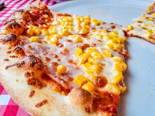 A piece of delicious pizza on a white plate at the table, close-up