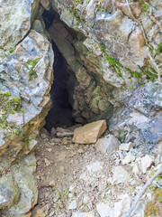 A small cave entrance nestled among rocks in the Alps, Switzerland. Natural rock