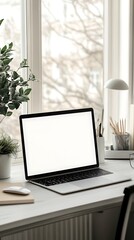 Fototapeta premium Laptop with blank screen on white desk near window and plants in a bright and airy workspace setup