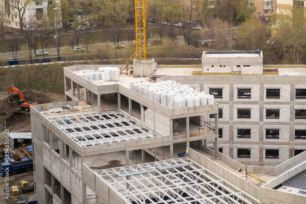 Poster construction site showcasing progress on a multi-story building with cranes and materials present in