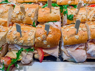 Fototapeta premium Turkey, Cheese, And Tomato Small Sandwiches Lined Up On A Silver Tray