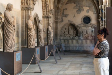 Tourist admiring ancient sculptures in the cloister of leon cathedral, a masterpiece of gothic...