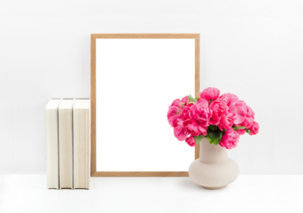 modern romantic mockup with wooden picture / photo frame, cream colored books and a bunch of roses in a vase on a white shelf or table against a bright wall, cut-out transparent space for your artwork