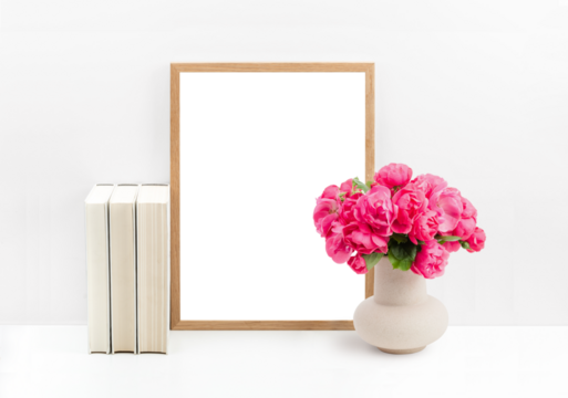 modern romantic mockup with wooden picture / photo frame, cream colored books and a bunch of roses in a vase on a white shelf or table against a bright wall, cut-out transparent space for your artwork