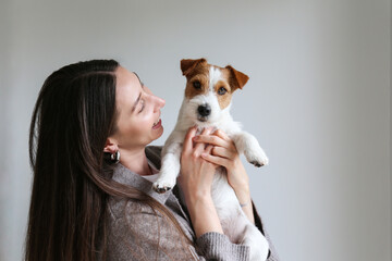 Brunette woman holding a dog. Copy space background.