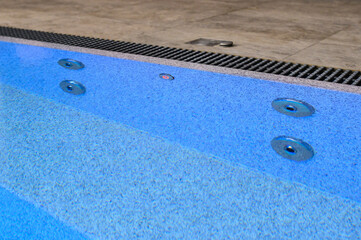 Overflow pool with clean transparent blue water. Hydromassage attraction. Close-up. Vacation outside the city
