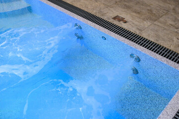 Overflow pool with clean transparent blue water. Hydromassage attraction in action. Close-up. Vacation outside the city