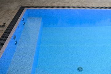 Overflow pool with clean transparent blue water. Hydromassage attraction with a bench. Close-up. Rest outside the city