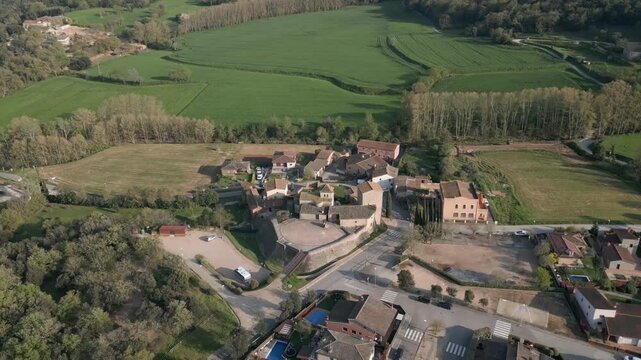 Vista a&eacute;rea del pueblo de Palol de Revardit, en Girona, rodeado de naturaleza y colinas verdes bajo cielo despejado.