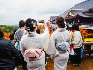 Women in Kimono Taking Photos at Kiyomizu-dera Temple in Kyoto during Autumn