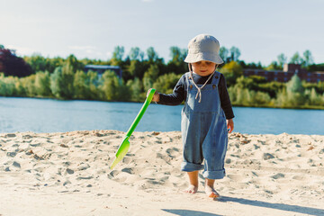 A joyful and playful toddler is at the beach, thoroughly enjoying the sunny day while holding a...