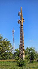 Weathered concrete utility pole with hexagonal cutouts and broken ceramic insulators stands unused...