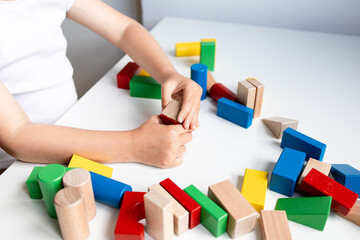 Young caucasian child playing with colorful wooden blocks on white table