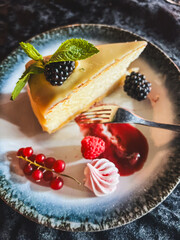 Piece of cheesecake with fresh berries and mint on dark background