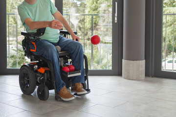 Boccia player with disability sitting in electric wheelchair, engaging in a game, throwing ball...