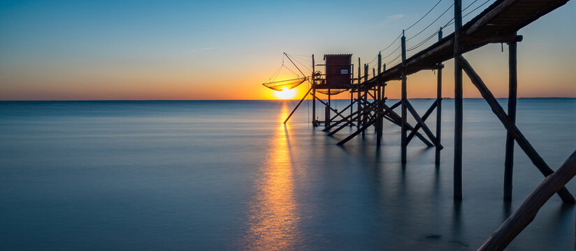 Traditional fishing hut (Carrelet) with wooden walkway on the Atlantic coast at sunset, Esnandes France