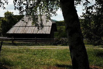 Traditional Serbian wooden barn surrounded by a wooden fence and lush greenery. Ethno village Staro...