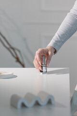 Beige manicured hand holding nail polish bottle, elegant beauty salon close-up concept