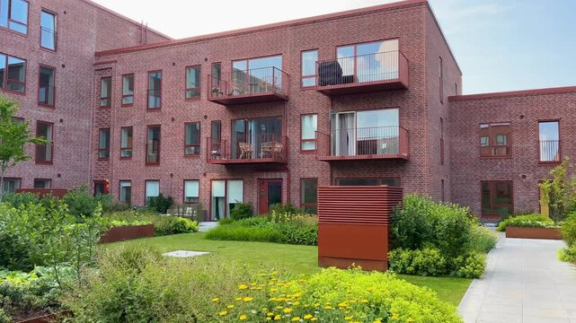 Herning, Denmark - June 12, 2025: Modern architecture apartments in Denmark summer days. Modern block of flats. A large building with a courtyard in the middle. Danish architecture design. Houses  - Powered by Adobe