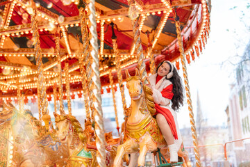 Festive woman in red dress enjoying a colorful carousel ride during holiday season at a joyful...