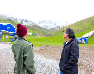 Two friends gazing at snowy mountains while exploring a serene landscape in spring