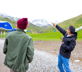 Two men discussing scenic mountain views on a chilly day in a ski resort