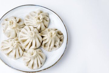 Plate with traditional georgian khinkali (dumplings) isolated on white background. Flat lay, copy space.