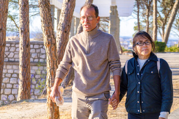 Couple enjoying a peaceful stroll in a sunlit park surrounded by tall trees and natural beauty