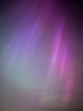 abstract pink and purple background with rays of aurora borealis or northern lights display in night sky with stars