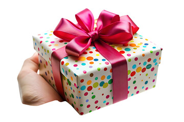 A hand holds a gift box wrapped in white paper with colorful polka dots and a large fuchsia ribbon bow isolated on a transparent background