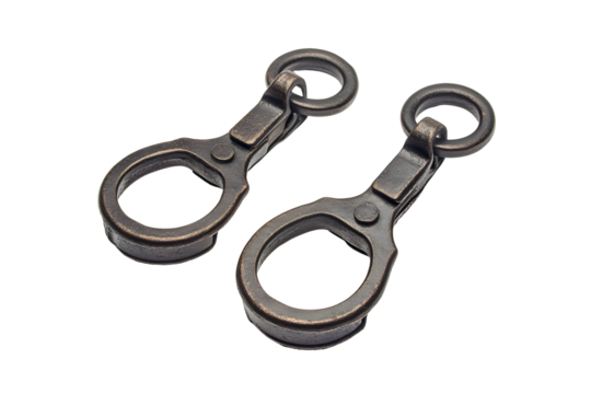 Close-up of two antique-looking metal trigger snaps against a dark background