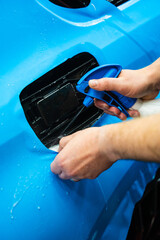 Detailing experts use hydration spray for controlled application of blue PPF film. Detailer uses...