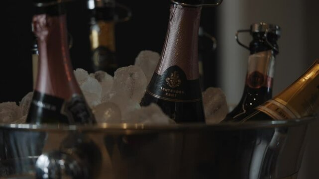 A silver bucket filled with ice and champagne bottles. The champagne bottles are in a row and are all different sizes
