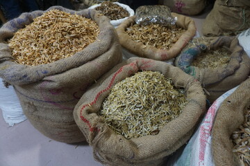 Mixed dried fish are displayed and sold at a fish market. Different types of dried fish along with...