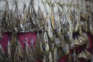 Naklejka premium Mixed dried fish are displayed and sold at a fish market. Different types of dried fish along with hilsa are sold by a street vendor. All types of dried salted fish in the Asian biggest seafood market
