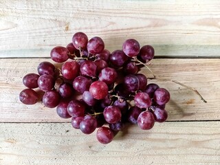 bunch of pink large grapes on a wooden background, top view, flat lay 