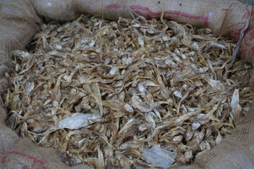 Mixed dried fish are displayed and sold at a fish market. Different types of dried fish along with...