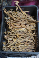 Mixed dried fish are displayed and sold at a fish market. Different types of dried fish along with...