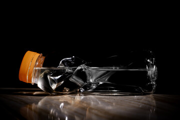 Crushed Plastic Bottle Trash Isolated on Dark Background – Environmental Waste Concept