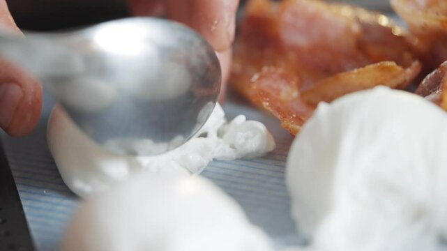 A close up of a plate of white cream puffs. The cream puffs are piled on top of each other and there is a spoon on the left side of the plate. Scene is light and playful