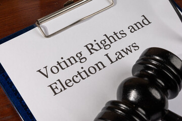 A legal document titled "Voting Rights and Election Laws" is placed neatly on a wooden desk, accompanied by a judge’s gavel, symbolizing authority and legal enforcement.