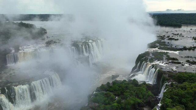 Aerial view of cascading Iguazu Falls enveloped in rising spray and lush jungle