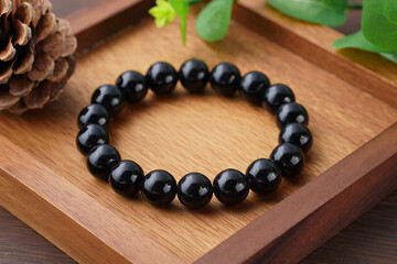 Elegant black bead bracelet resting on a wooden tray in a natural setting