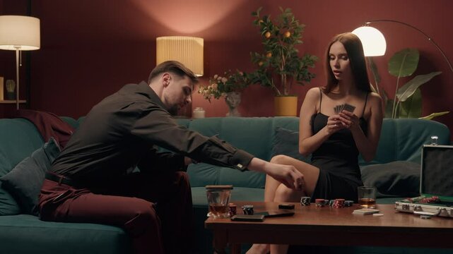 Date night party Caucasian couple playing poker drinking gambling man male boyfriend holding cards bet woman female girlfriend betting going all-in game competition addiction tournament dating at home